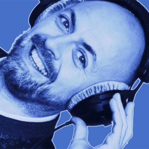 Blue filtered portrait of a man from DAVID Systems smiling, wearing headphones and holding them with his left hand