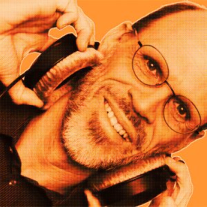 Orange-filtered portrait of Markus H. smiling, wearing headphones and holding them with both hands