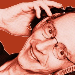 Red-filtered portrait of Stefan from DAVID Systems smiling, wearing headphones and holding them with his right hand