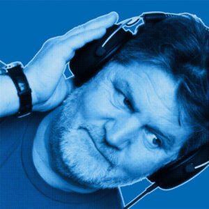 Blue-filtered portrait of Vincent from DAVID Systems wearing headphones and holding them with his right hand