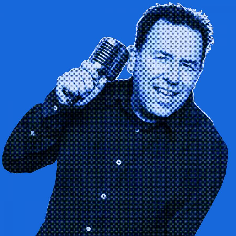 Blue-filtered picture of a man smiling and holding a microphone to his ear