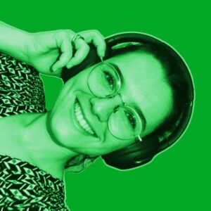 Green-filtered portrait of Camille from DAVID Systems smiling, wearing headphones, and holding them with her right hand